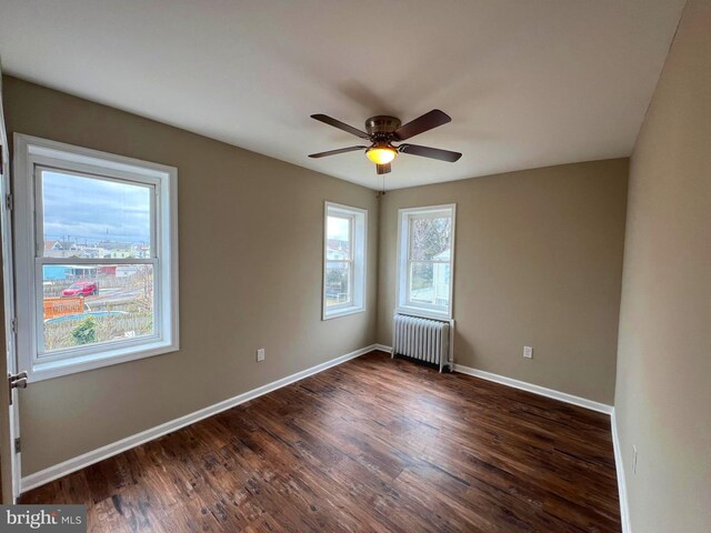 unfurnished bedroom with brick wall, radiator heating unit, and dark hardwood / wood-style floors