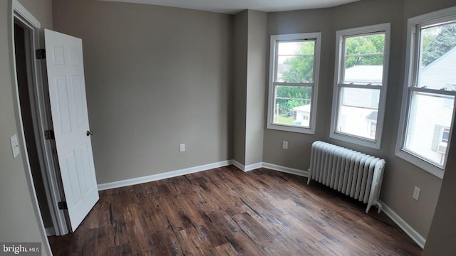 empty room featuring radiator and hardwood / wood-style flooring