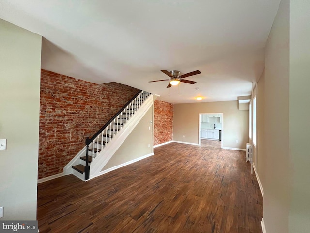 unfurnished living room with brick wall, dark wood-type flooring, radiator, and ceiling fan