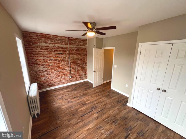 empty room with ceiling fan, radiator, dark hardwood / wood-style flooring, and plenty of natural light