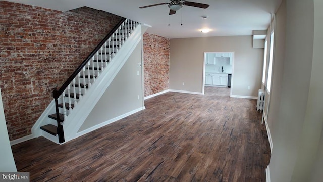 interior space featuring radiator, ceiling fan, sink, hardwood / wood-style floors, and brick wall