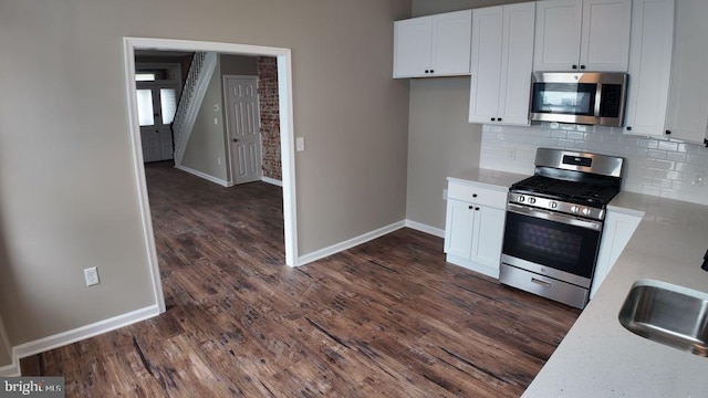 kitchen featuring appliances with stainless steel finishes, white cabinetry, dark hardwood / wood-style floors, and decorative backsplash