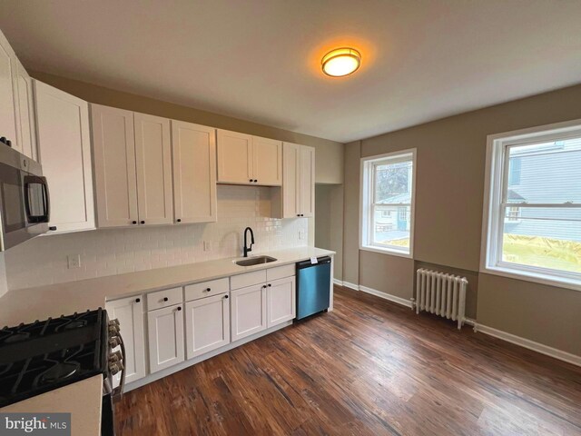 kitchen featuring gas stove, radiator heating unit, dark hardwood / wood-style floors, and a healthy amount of sunlight