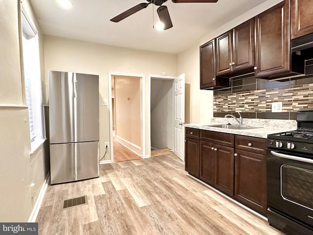 kitchen with ceiling fan, light hardwood / wood-style flooring, backsplash, stainless steel refrigerator, and black range with gas cooktop