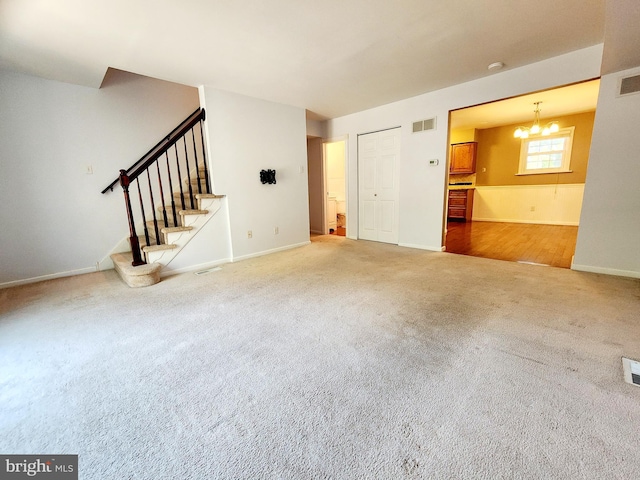 unfurnished living room featuring a notable chandelier and carpet floors