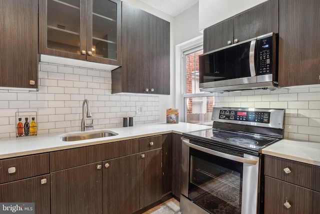 kitchen with sink, backsplash, appliances with stainless steel finishes, and dark brown cabinets