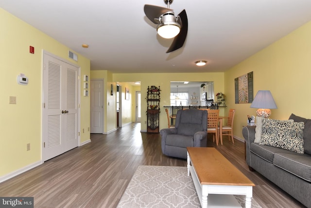 living room with dark wood-type flooring and ceiling fan