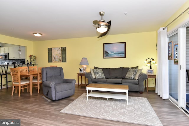 living room featuring ceiling fan and dark hardwood / wood-style flooring