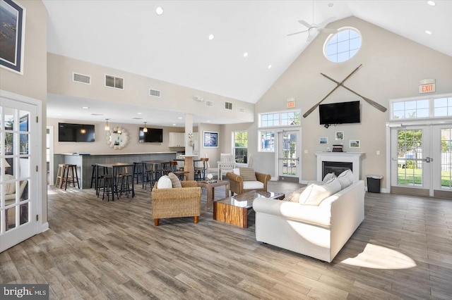 living room with high vaulted ceiling, hardwood / wood-style floors, ceiling fan, and french doors