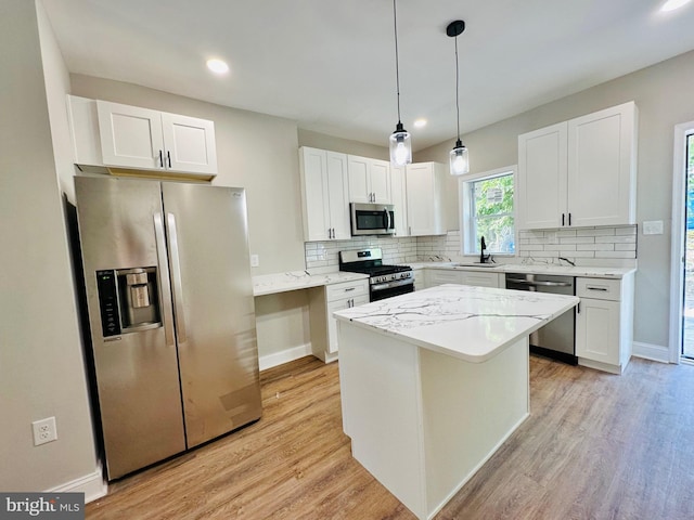 kitchen with a kitchen island, appliances with stainless steel finishes, white cabinets, and a sink