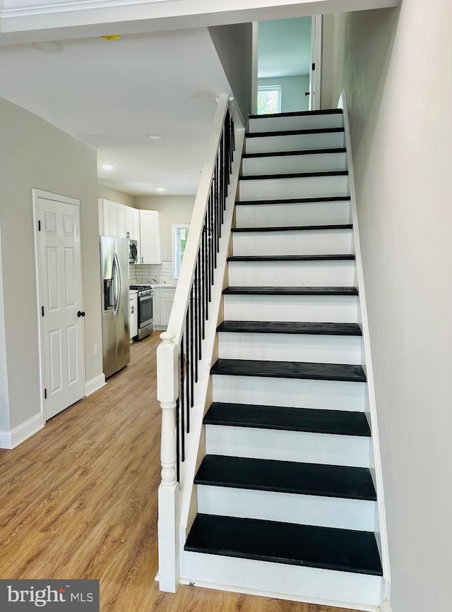 stairs with recessed lighting, baseboards, and wood finished floors