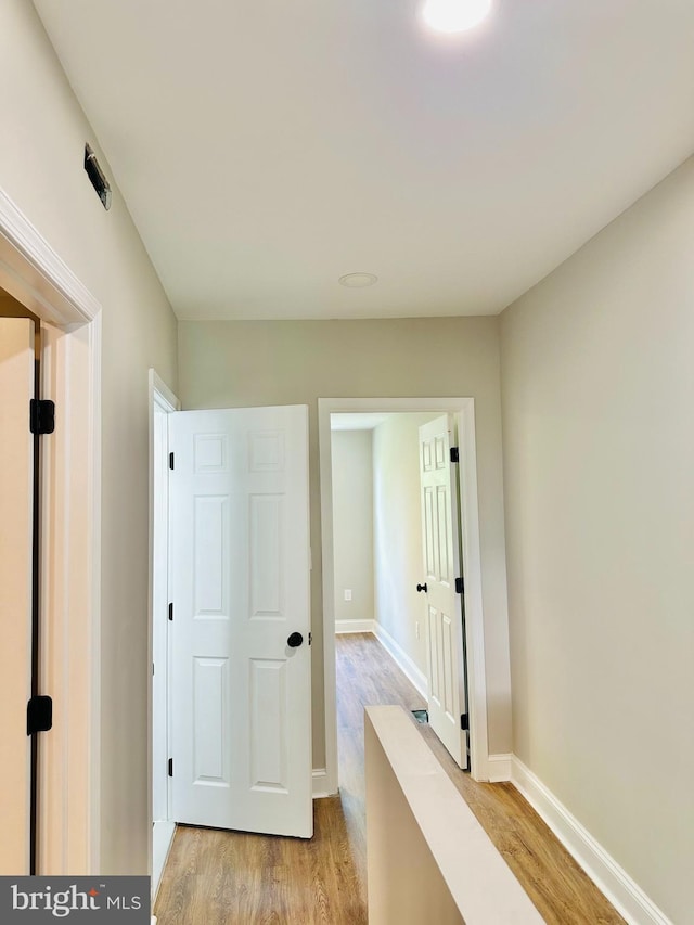 corridor with light wood-style floors and baseboards