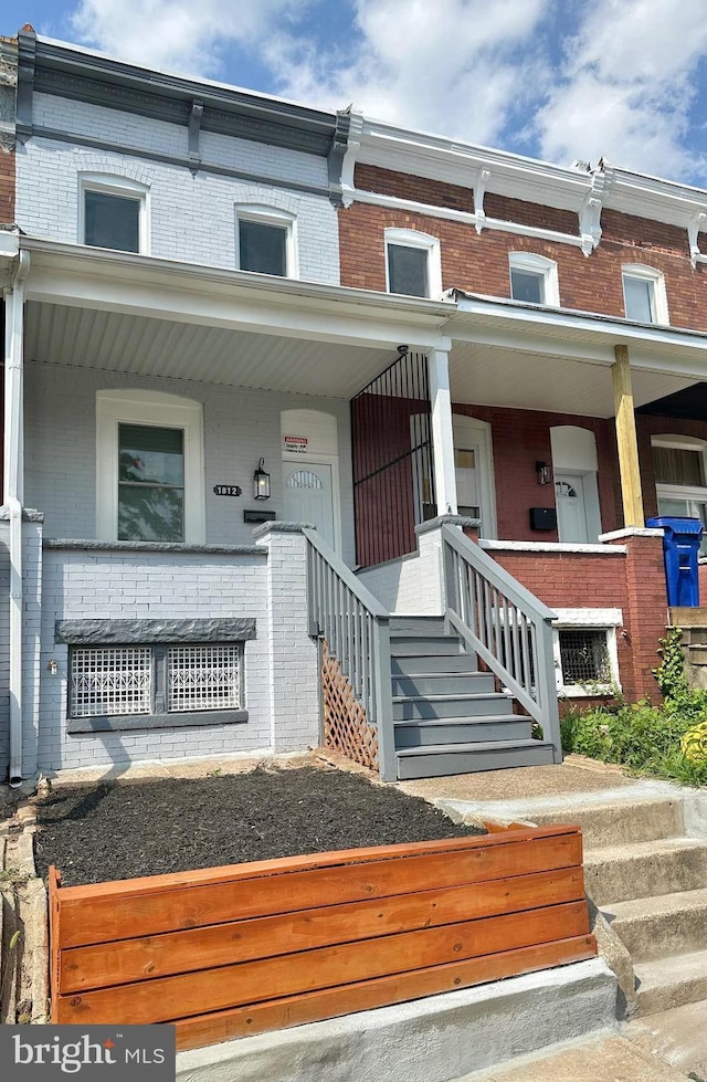 entrance to property with brick siding and a porch