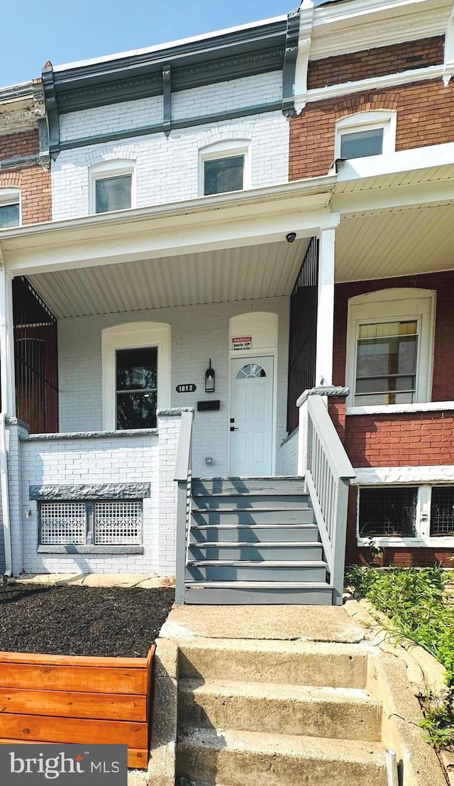 property entrance with a porch and brick siding