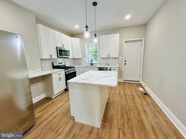 kitchen featuring stainless steel appliances, white cabinetry, and light stone counters