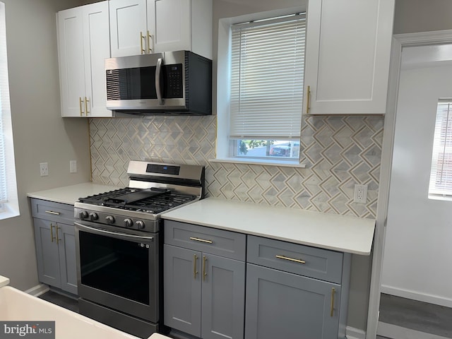 kitchen with hardwood / wood-style floors, backsplash, gas range, and gray cabinets