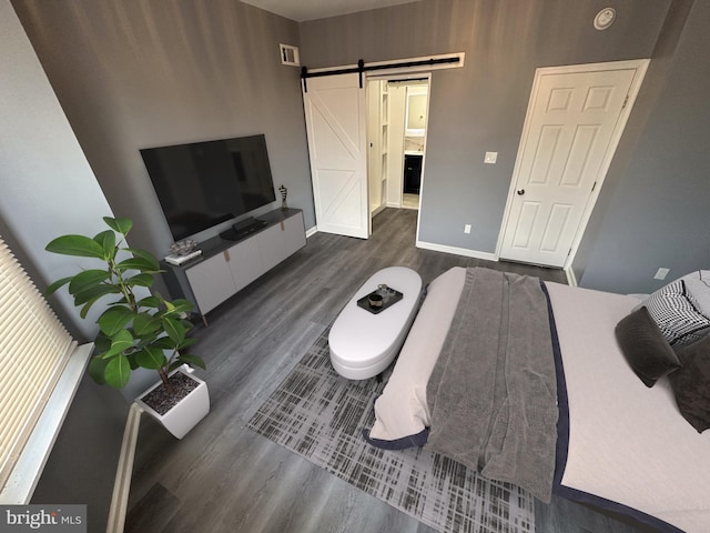 bedroom with dark hardwood / wood-style floors and a barn door