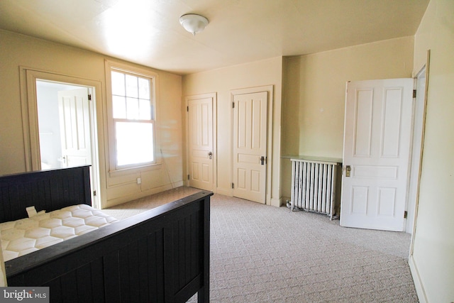 carpeted bedroom featuring multiple closets and radiator heating unit