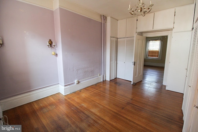 unfurnished bedroom featuring dark hardwood / wood-style flooring and a notable chandelier