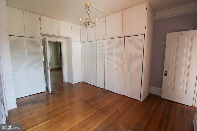 unfurnished bedroom with dark hardwood / wood-style floors and a chandelier