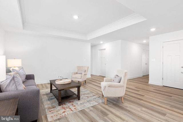 living room with recessed lighting, a raised ceiling, light wood-style flooring, and baseboards