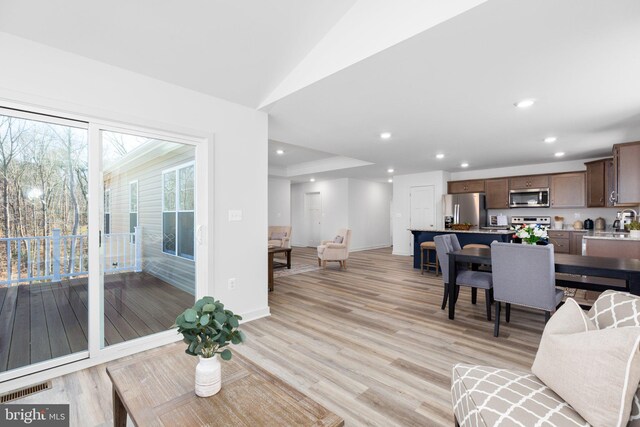 living room featuring lofted ceiling and light hardwood / wood-style floors