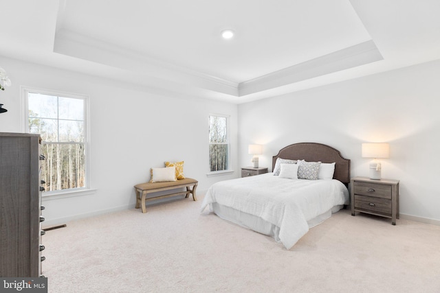 bedroom featuring light colored carpet, ornamental molding, and a tray ceiling