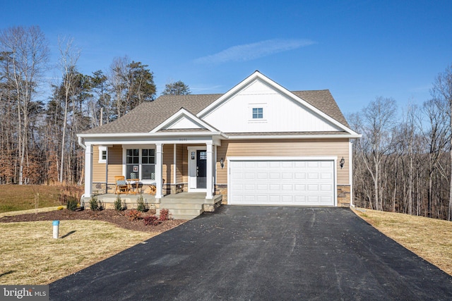 view of front of home with driveway, covered porch, a garage, and stone siding