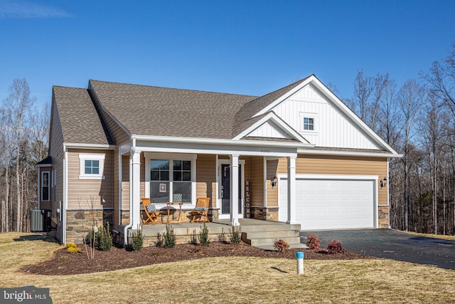 view of front of home featuring aphalt driveway, cooling unit, covered porch, a garage, and stone siding