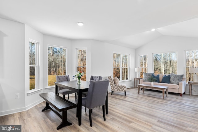 dining space with lofted ceiling, baseboards, and light wood-style floors