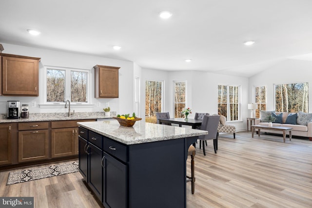 kitchen featuring a wealth of natural light, light stone counters, a kitchen island, and light hardwood / wood-style floors