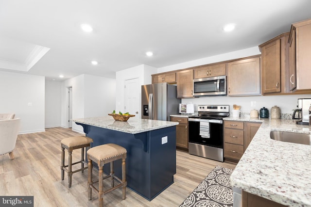 kitchen featuring a kitchen island, stainless steel appliances, a breakfast bar area, and light hardwood / wood-style floors