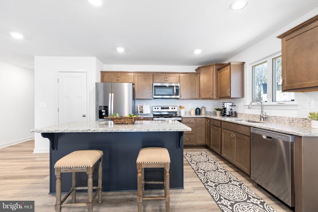 kitchen featuring light hardwood / wood-style flooring, appliances with stainless steel finishes, sink, a kitchen breakfast bar, and a kitchen island