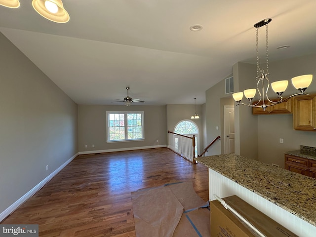 kitchen with pendant lighting, light stone counters, visible vents, and brown cabinets