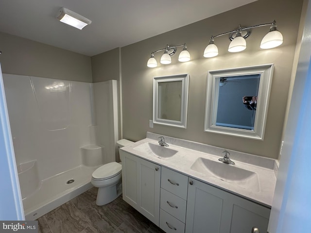 bathroom featuring double vanity, a sink, toilet, and walk in shower