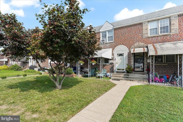 townhome / multi-family property with a front lawn and brick siding