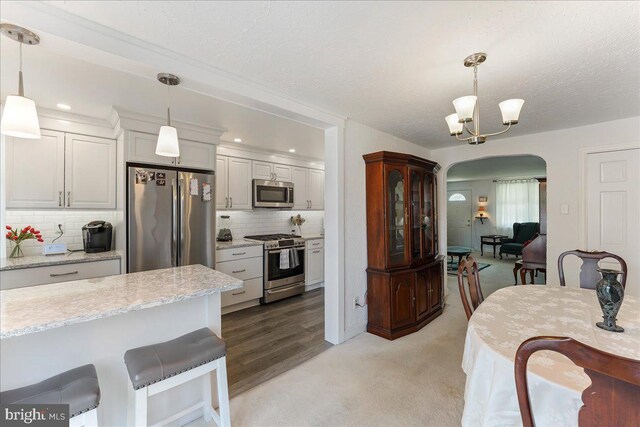 kitchen featuring pendant lighting, stainless steel appliances, decorative backsplash, and a chandelier