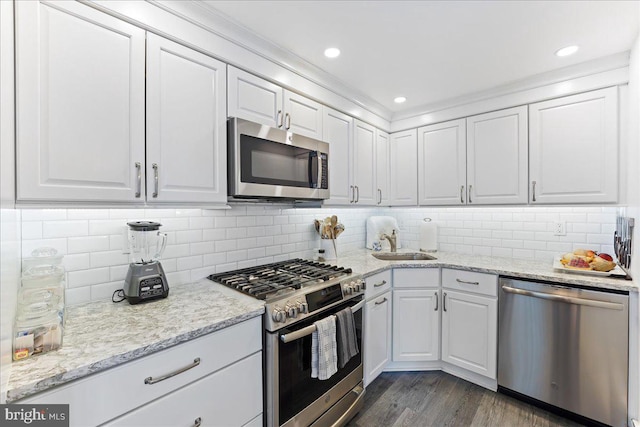 kitchen featuring white cabinetry, backsplash, stainless steel appliances, dark hardwood / wood-style flooring, and sink