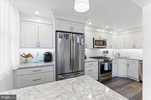 kitchen with dark wood-type flooring, backsplash, appliances with stainless steel finishes, and white cabinetry