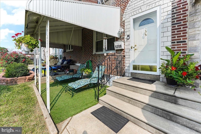 entrance to property with brick siding and a lawn