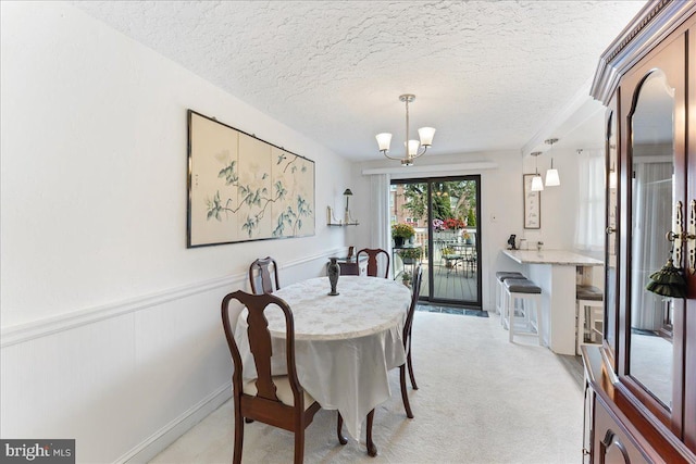 dining space with a notable chandelier, light carpet, and a textured ceiling