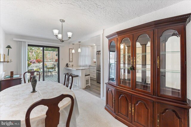 dining space with a textured ceiling, light hardwood / wood-style flooring, and a chandelier