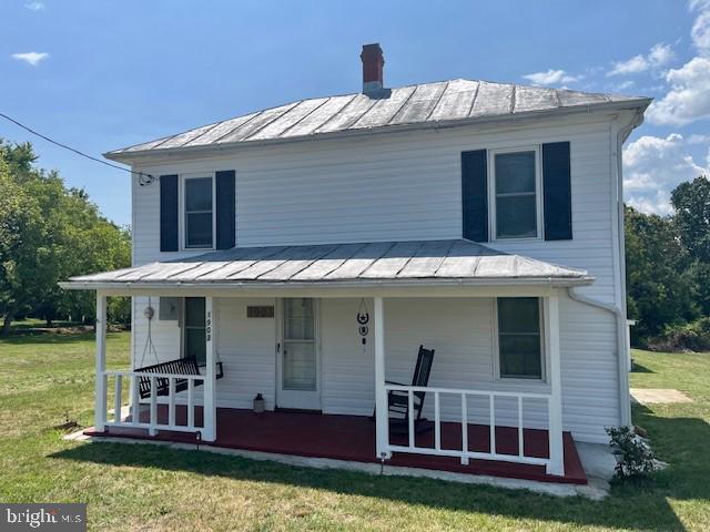 view of front facade featuring a porch, a front yard, a standing seam roof, and metal roof