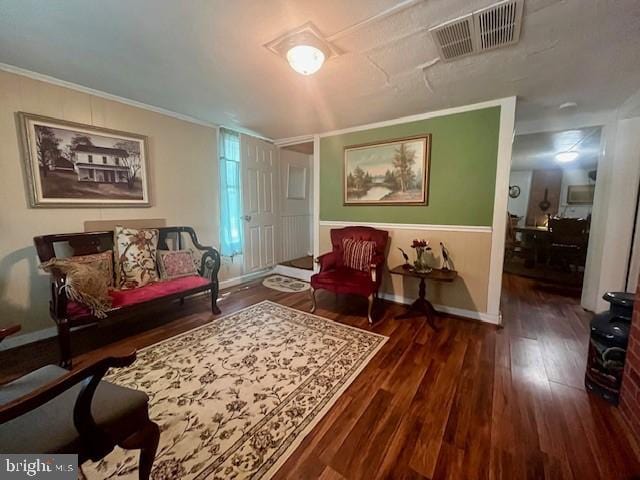 living room with ornamental molding, visible vents, baseboards, and wood finished floors