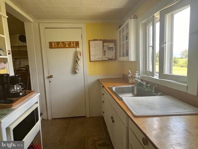 kitchen featuring white cabinets, a sink, and light countertops