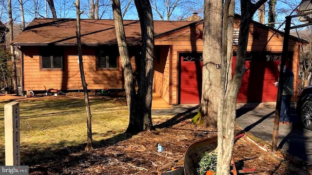 exterior space featuring a garage and a lawn