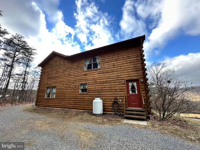 view of side of property with entry steps, gravel driveway, and log siding