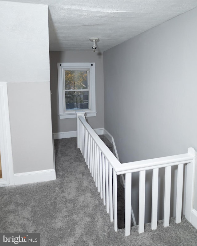 hall with a textured ceiling and carpet floors