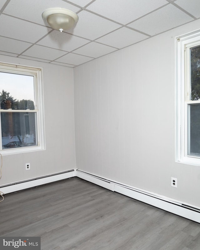 empty room with a healthy amount of sunlight, wood-type flooring, and a drop ceiling