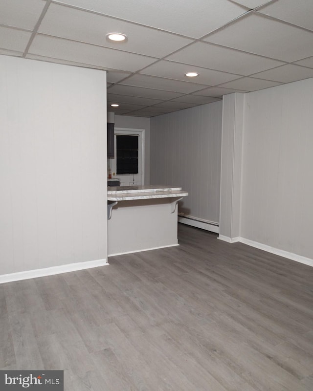 unfurnished room featuring a baseboard radiator and a drop ceiling